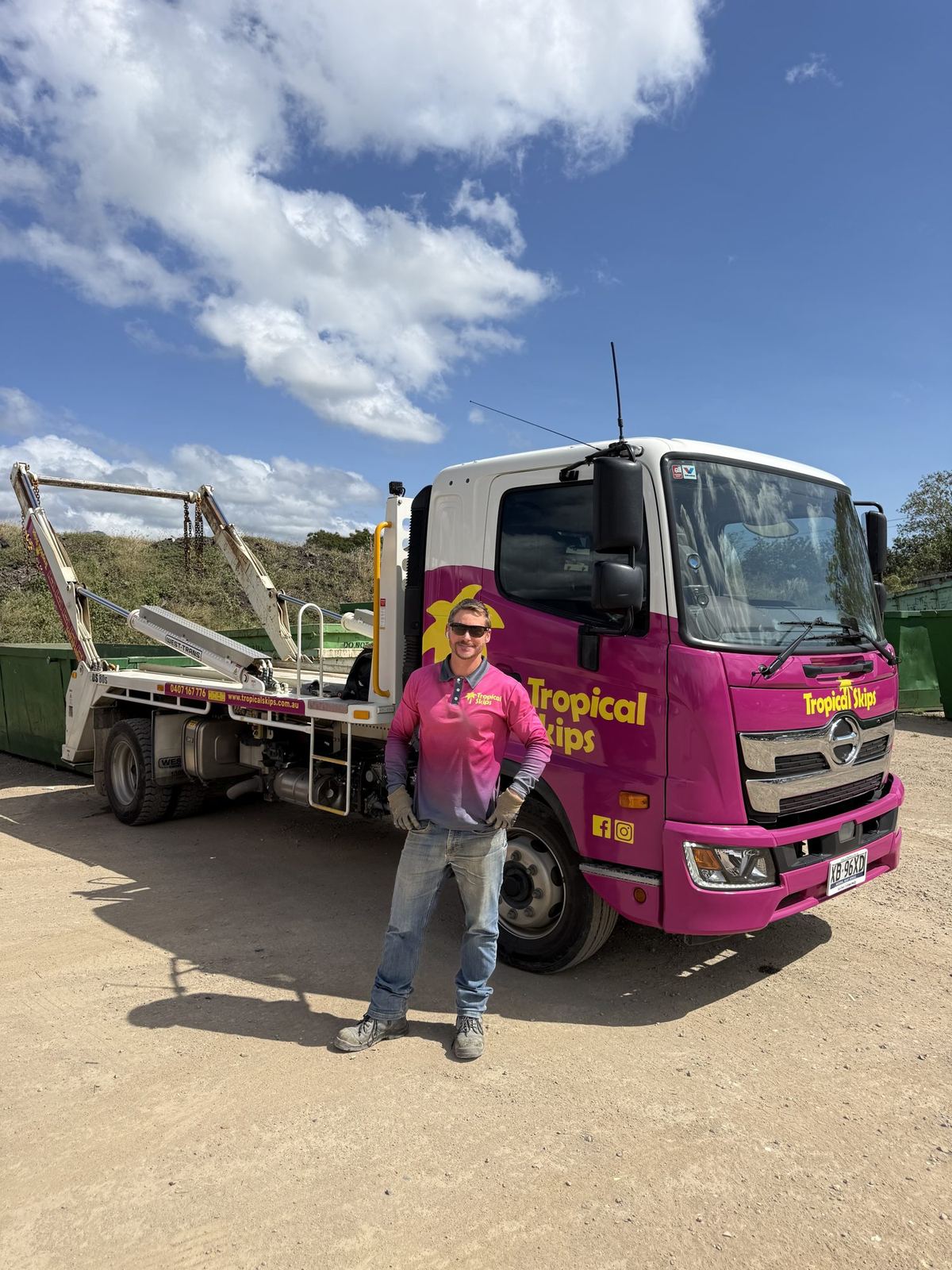 Driver climbing into the cab of a Tropical Skips truck