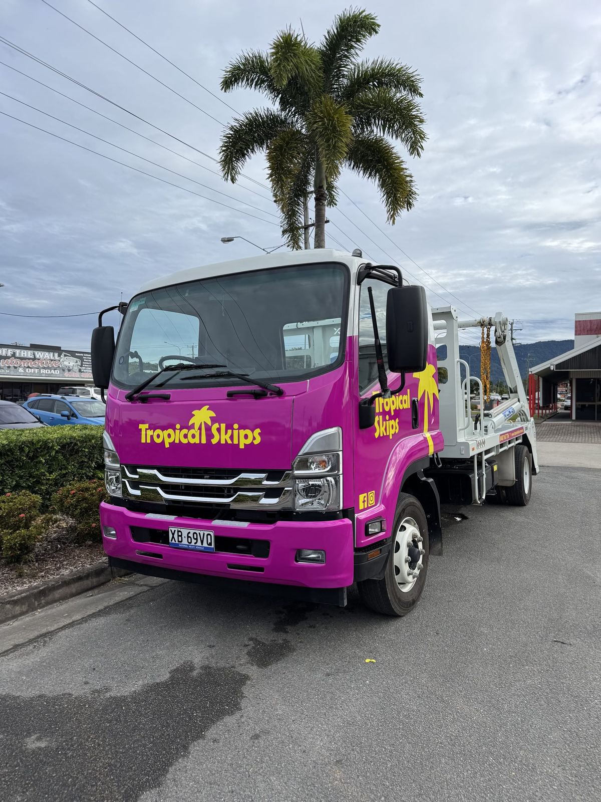 Tropical Skips truck front-on under a tall palm on a Cairns street
