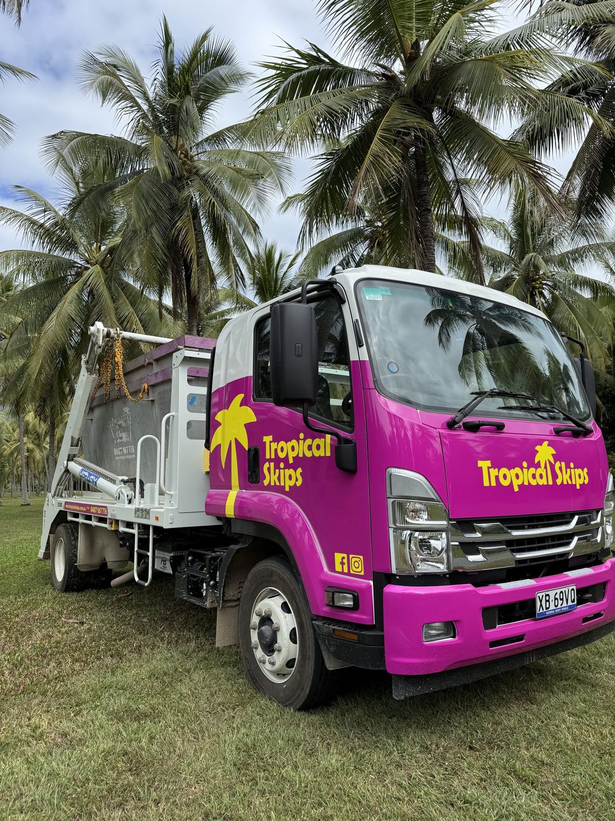 Magenta Tropical Skips truck cab between coconut palms