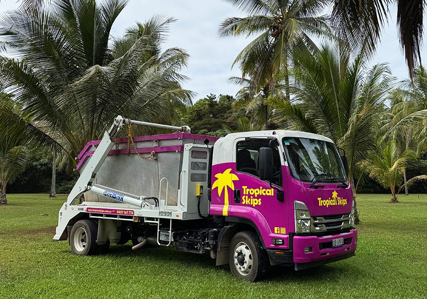 Tropical Skips magenta skip truck parked among coconut palms in Cairns